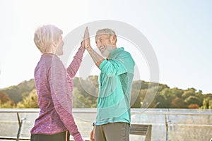 Partnership. Happy family couple, mature man and woman in sportswear giving high five after having workout in the city