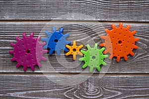 Parts of a color puzzle of gears are assembled into one. on wood texture background.