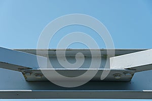 Parts of a modern metal bridge in close-up against a blue sky background. Metal structures connected by large bolts and nuts to a
