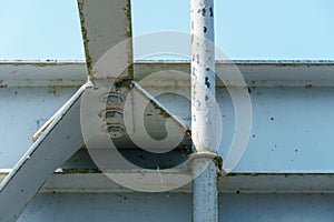 Parts of a modern metal bridge in close-up against a blue sky background. Metal structures connected by large bolts and nuts to a