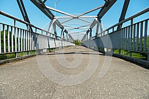 Parts of a modern metal bridge in close-up against a blue sky background. Metal structures connected by large bolts and nuts to a