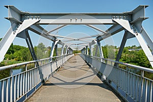 Parts of a modern metal bridge in close-up against a blue sky background. Metal structures connected by large bolts and nuts to a