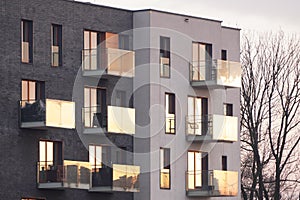 Parts of modern residential complexes in a European city in the sunset or dawn sun. Open balconies with glass railings,