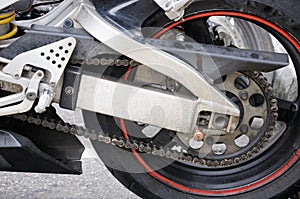 Parts of a motorcycle focusing on the rear wheel and motor chain link