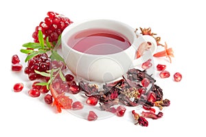 Parts of pomegranate with pomegranate seeds and leaves, flowers, dry tea of carcade and full cup of tea on white