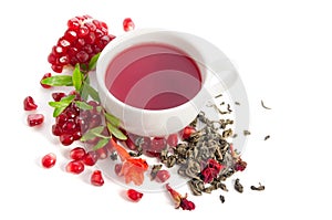 Parts of a pomegranate with pomegranate seeds and leaves, flowers, dry tea of carcade and full cup of tea on white