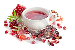 Parts of pomegranate with pomegranate seeds and leaves, flowers, dry tea of carcade and full cup of tea on white photo