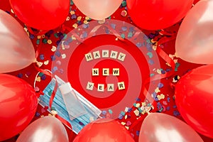 Party background with Coronavirus and happy new year written in English with wooden letters and decorated with face mask,