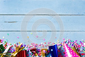 Party background. Party caps and confetti on blue wooden background.