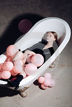 Party balloons in bubbles bath tub. woman relax in bath. fashion model in autumn coat. hygiene and spa treatment. having