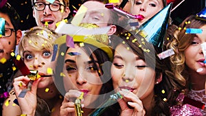 Party blower, confetti and group of people enjoying time together. Holiday event, celebration and happy friends blowing