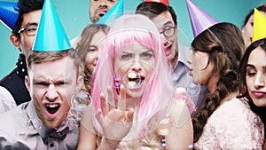 Party, bubbles and group of friends dance in studio isolated on a blue background. Diversity, celebration event and