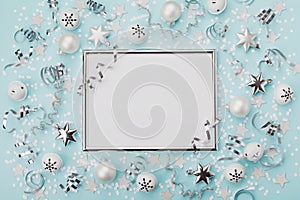 Party carnival christmas background decorated silver frame with confetti, balls and star on turquoise desk top view. Flat lay.