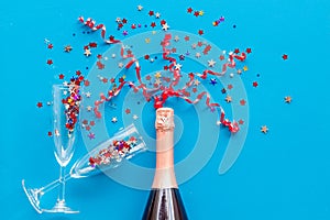 Party with champagne bottle, glasses and colorful party streamers on bllue background top view