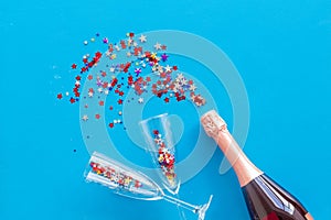 Party with champagne bottle, glasses and colorful party streamers on bllue background top view