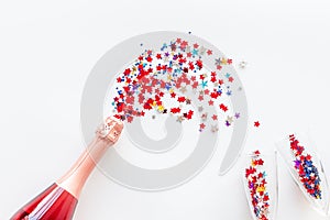 Party with champagne bottle, glasses and colorful party streamers on white background top view