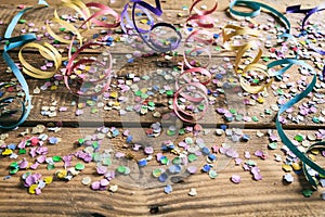 Colorful carnival confetti and serpentines on wooden background
