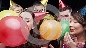 Party, confetti and people with balloons in studio for festive celebration, social event and birthday on black