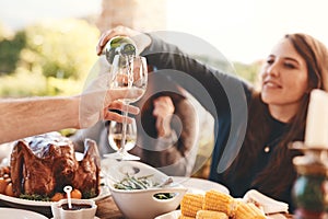 Party, dinner and woman pouring wine in a wine glass to cheers at an outdoor celebration feast. Champagne, toast and