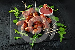 Party finger food pigs in blankets on toothpicks with ketchup sauce and wild rocket leaves