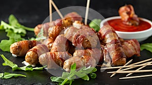 Party finger food pigs in blankets on toothpicks with ketchup sauce and wild rocket leaves