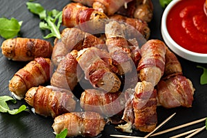 Party finger food pigs in blankets on toothpicks with ketchup sauce and wild rocket leaves