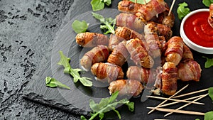 Party finger food pigs in blankets on toothpicks with ketchup sauce and wild rocket leaves