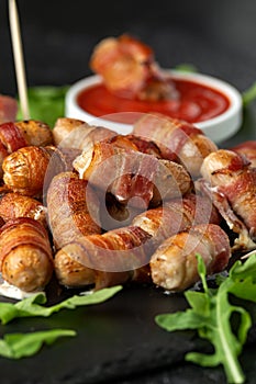 Party finger food pigs in blankets on toothpicks with ketchup sauce and wild rocket leaves