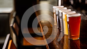 Party with friends in pub. Row of glasses of beer of different sorts on bar counter in interior