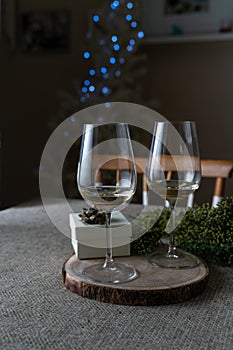 Party gift box and glasses of white wine with defocused Christmas tree lights. Christmas at home