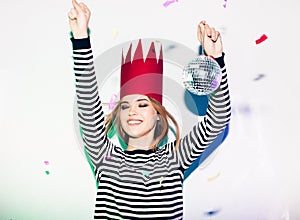 Party girl in colorful spotlights and confetti smiling on white background celebrating brightful event, wears stripped