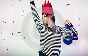 Party girl in colorful spotlights and confetti smiling on white background celebrating brightful event, wears stripped