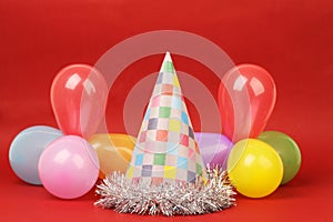 Party hat and party balloons on red background