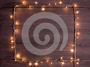 Party lights decoration. Wooden background with christmas lights garland, frame with copy space for a text