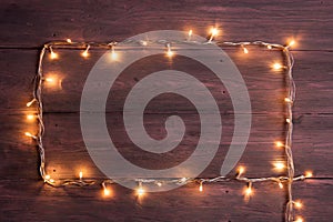 Party lights decoration. Wooden background with christmas lights garland, frame with copy space for a text