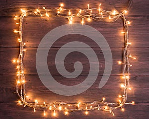 Party lights decoration. Wooden background with christmas lights garland, frame with copy space for a text