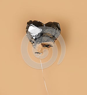 Party is over deflated silver heart balloon object  on beige background with shadow
