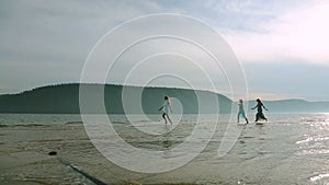 Party and people concept - group of smiling teen girls jumping on beach. Silhouette of three young women running around