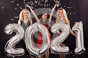 Party, people and new year holidays concept - cheerful young women celebrating new years eve 2021