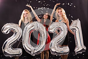 Party, people and new year holidays concept - cheerful young women celebrating new years eve 2021