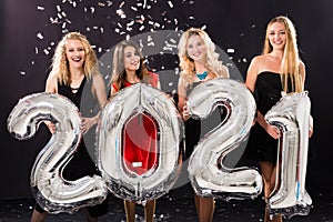 Party, people and new year holidays concept - cheerful young women celebrating new years eve 2021