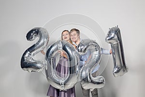 Party, people and new year holidays concept - woman and man celebrating new years eve 2021