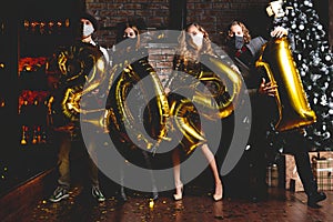 Party, people and new year holidays concept - women and men in protective medical mask celebrating new years eve 2021