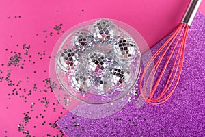 Party rave, greeting card concept. Pink kitchen whisk shaked decorative shining disco balls into small silver stars on