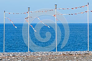 Party or season of vacations is over - an empty sea beach with pillars for festive flags.