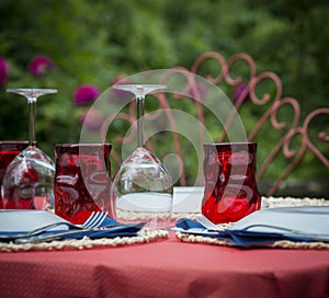 Party table outside red tablecloth and drinking glasses