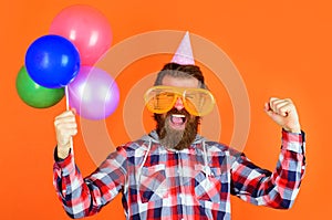 Party time. Joy, fun and happiness concept. Happy Man with balloons. Bearded man in party cap and big glasses.