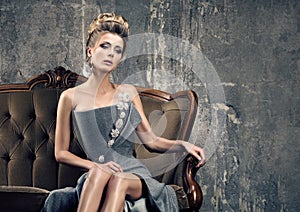 Party time sadness. Lonely beautiful young woman in grey evening dress sitting