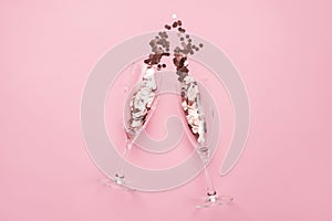 Partying concept. Top above overhead view close up photo of two champagne flutes full of confetti isolated on patel pink