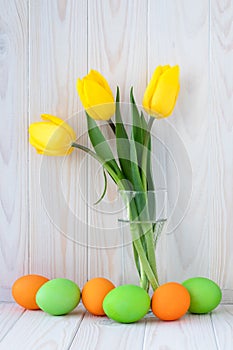 Paschal card, easter eggs and bouquet of spring flowers, decoration design. Light wooden background. Holiday, festive still life